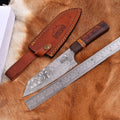 Animas Forge Damascus Knife with leather sheath and ruler on a wooden surface