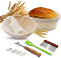 Round rattan banneton proofing basket with linen liner, bread lame, extra blades, dough scraper, and brush for artisan sourdough baking.